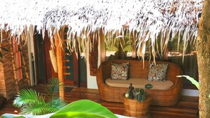 A thatched-roof outdoor seating area with a cushioned sofa and a woven basket. - La Colonial Resort - Adults Only (El Nido)