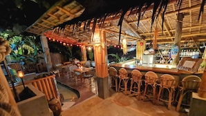 An outdoor bar area with wooden furniture and a thatched roof. - La Colonial Resort - Adults Only (El Nido)