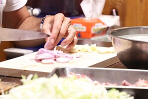 A person chopping vegetables on a cutting board. - Guest House Ilonggo (Tsu)