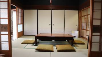 Una habitación japonesa tradicional con suelo de tatami, una mesa de madera baja y puertas correderas.