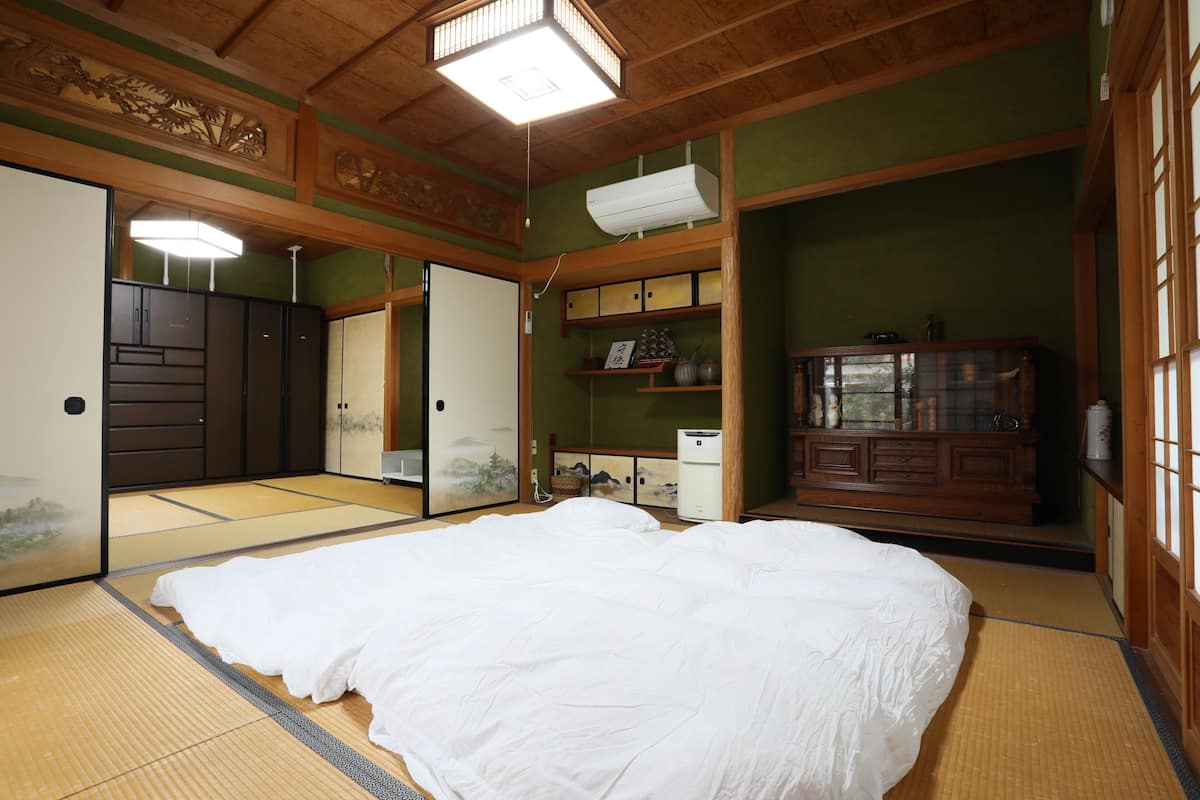 A traditional Japanese room with tatami flooring, a large bed, sliding doors, and a wooden cabinet.