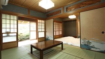 Una habitación japonesa tradicional con suelo de tatami, una mesa de madera baja, puertas correderas y vistas a un paisaje montañoso.