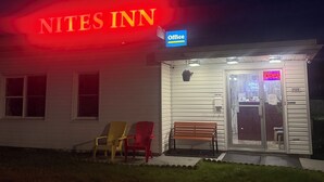A building with a neon sign reading 'NITES INN' and an 'Office' sign above the entrance. There are two chairs and a bench outside. - Nites Inn Motel (Cornwall)