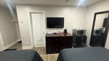 A hotel room with two beds, a TV, a dresser, and a microwave.