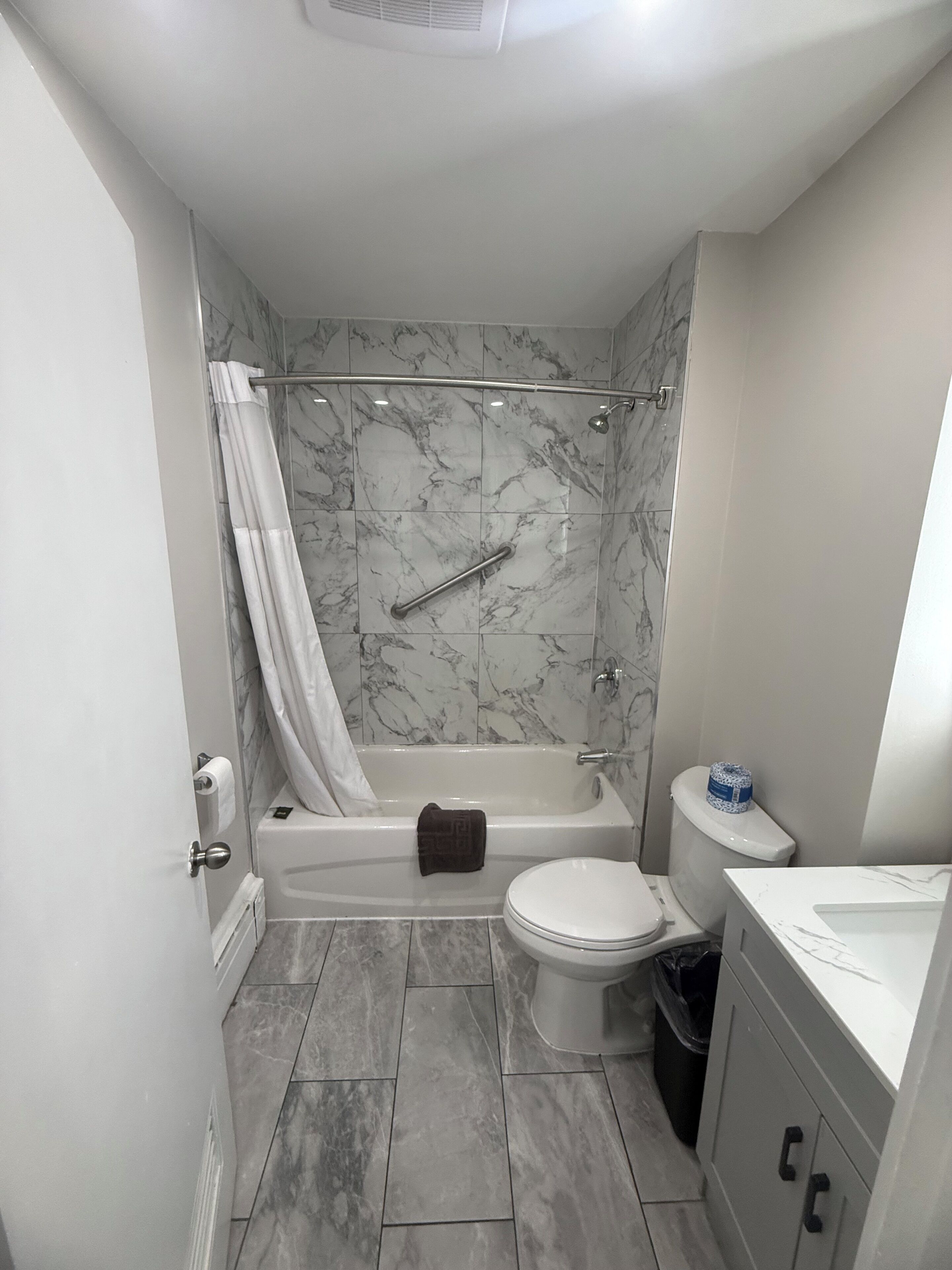 Kombinasi shower/bathtub, pancuran hujan, jubah mandi, dan handuk