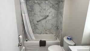 A bathroom with a bathtub, toilet, and vanity. - Nites Inn Motel (Cornwall)
