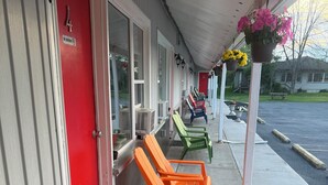 A motel with a red door, numbered room 4, and outdoor seating with chairs in various colors. - Nites Inn Motel (Cornwall)