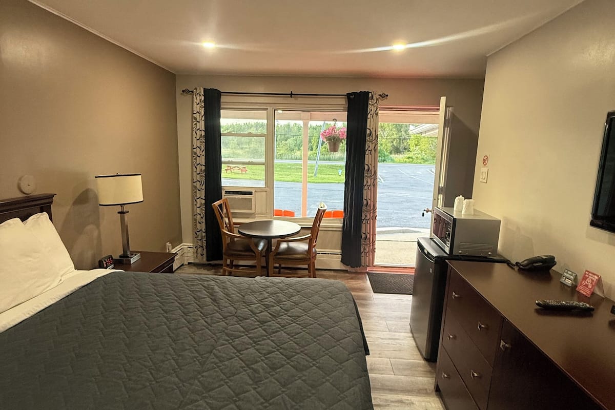 Habitación de hotel con cama, escritorio, silla, televisión y vistas al exterior.