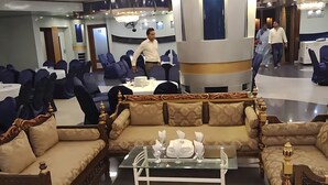 Un amplio salón con un gran sofá, una mesa de centro de vidrio y elegantes lámparas de araña.