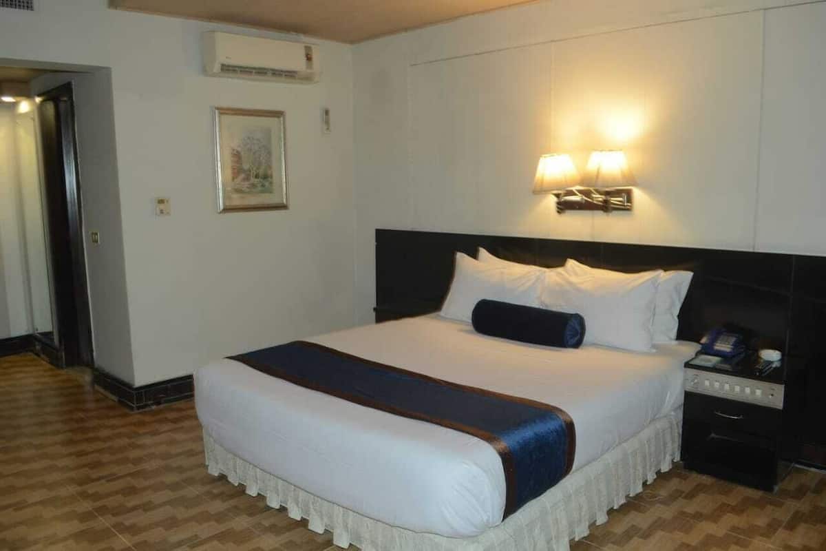 A hotel room with a large bed, a bedside table with a lamp, and a framed picture on the wall.