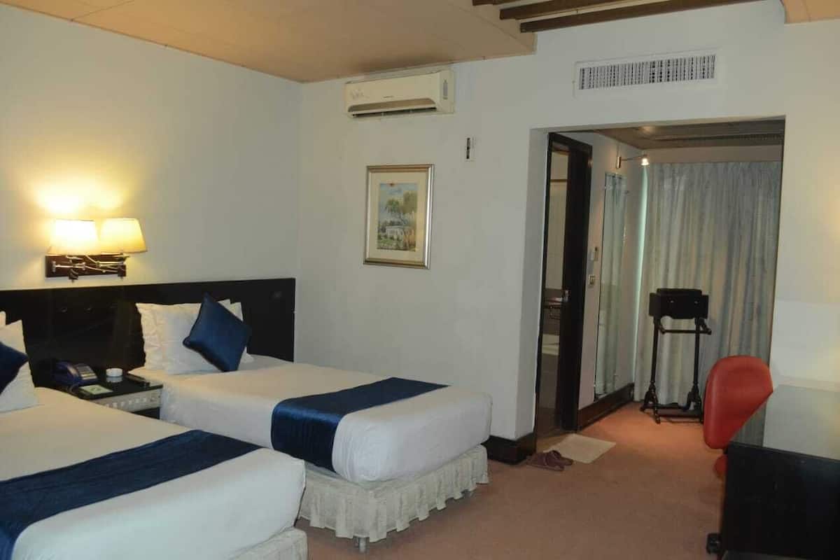A hotel room with two beds, a desk, a chair, and a picture on the wall.