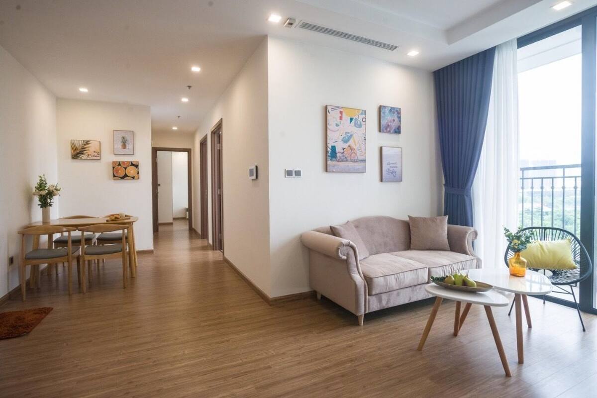 Una sala de estar moderna con un sofá, una mesa de comedor con sillas y obras de arte en las paredes.