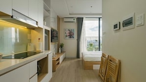 Een moderne hotelkamer met kitchenette, een bed, een klein bureau en een balkon met uitzicht.