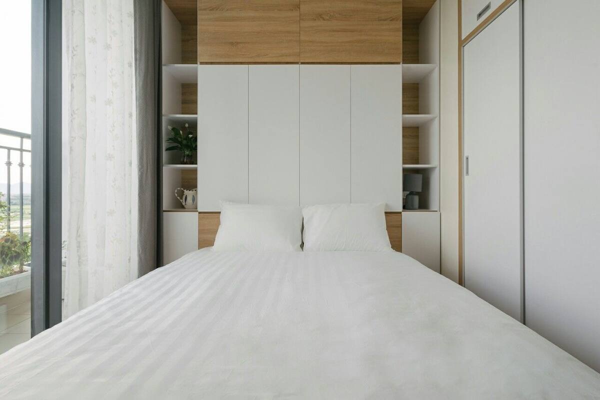 Un dormitorio moderno con una cama grande, estanterías empotradas y vistas al exterior.