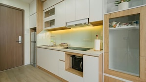Een moderne keuken met witte kastjes, een inbouwoven en een magnetron.