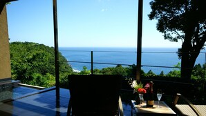 A balcony with a view of the ocean, a pool, and outdoor seating. - Gensen to Hanare no Oyado Tsuki (Ito)