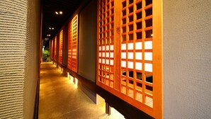 A corridor with traditional wooden lattice doors and a textured wall. - Gensen to Hanare no Oyado Tsuki (Ito)