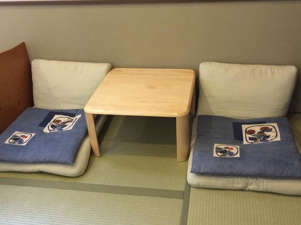 Una habitación con dos zonas de estar con esteras de tatami, cada una con un cojín decorado con motivos florales.