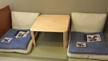 Una habitación con dos zonas de estar con esteras de tatami, cada una con un cojín decorado con motivos florales.