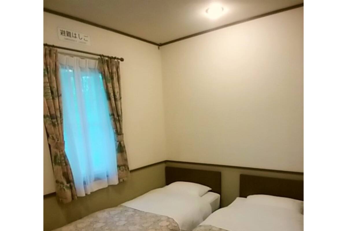 Ein Zimmer mit zwei Einzelbetten, einem Fenster mit Vorhängen und einem Schild über dem Fenster.