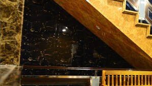 Een marmeren trap met een gouden leuning en een houten bankje.