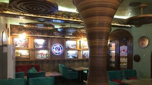 Een restaurantinterieur met teal stoelen, een centrale kolom en een neonbord aan de muur.