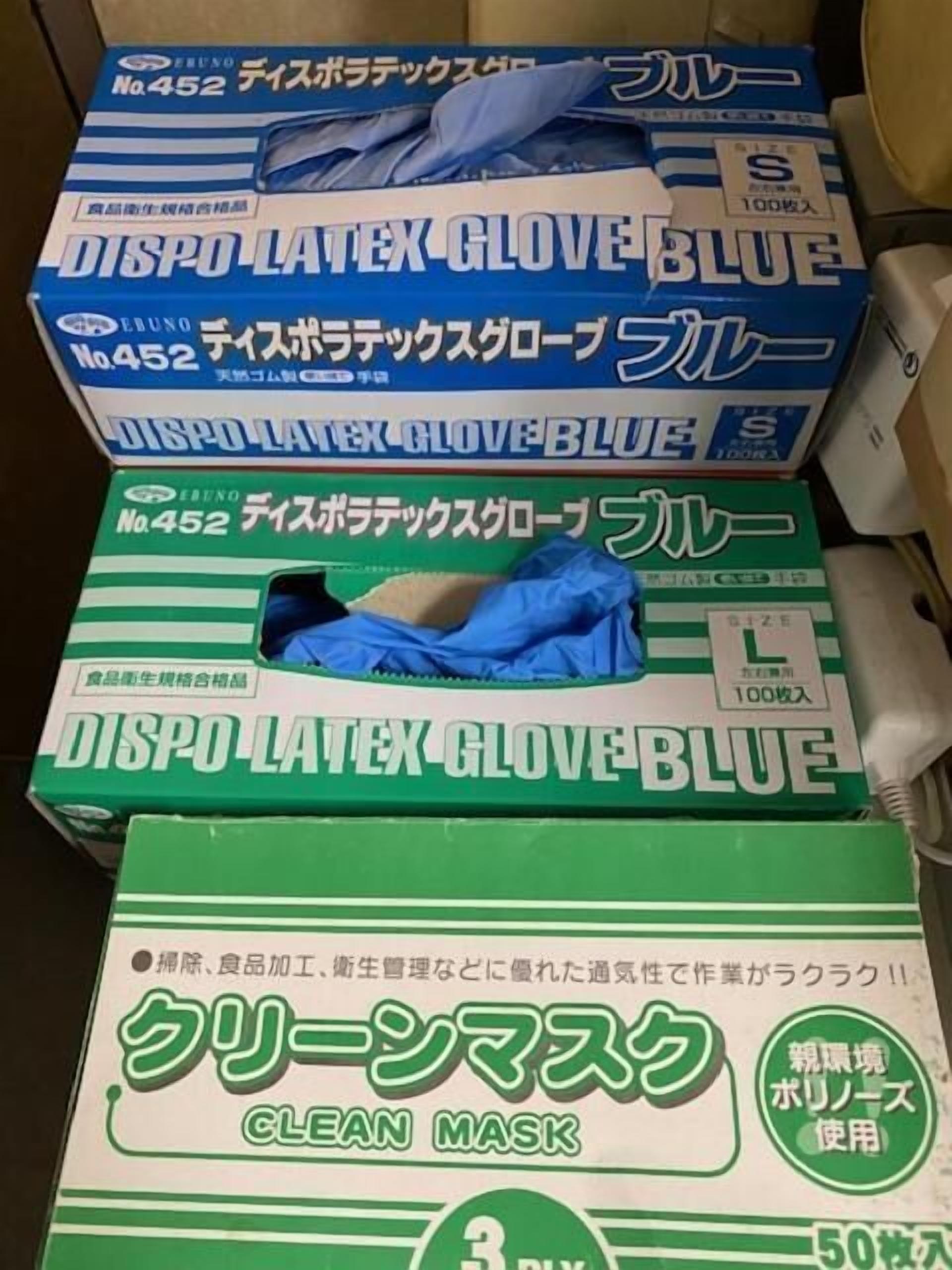 A box of disposable latex gloves in blue and green, and a box of a clean mask.