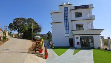 A modern hotel with a two-story structure, a central vertical window, and a well-maintained lawn.