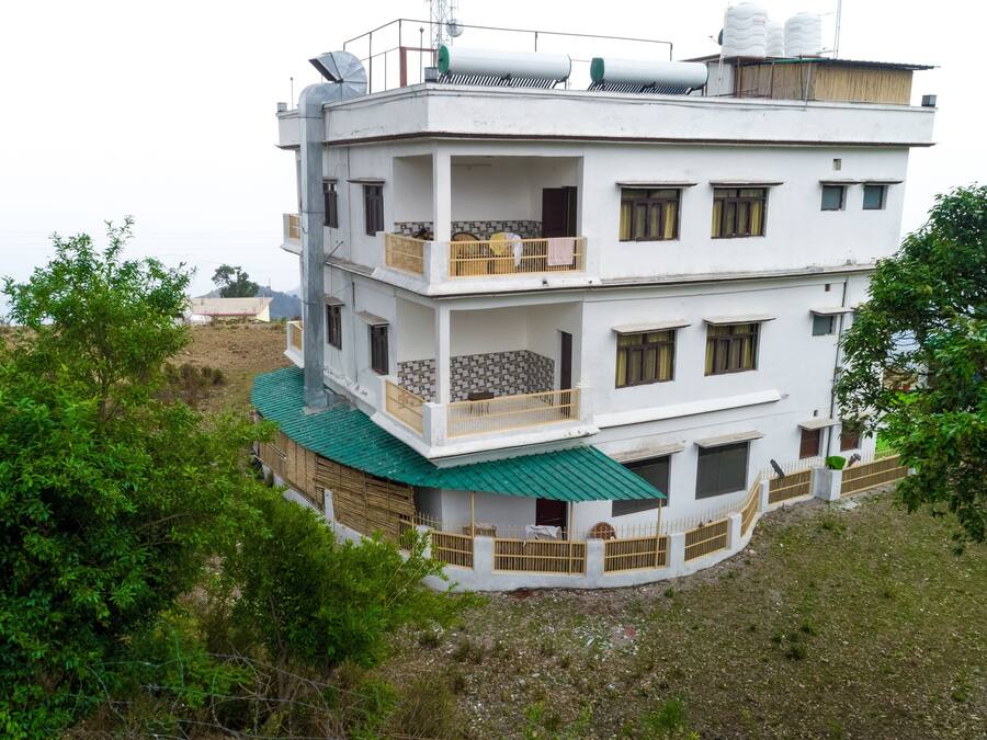 A multi-story building with balconies, a green roof, and a white exterior.