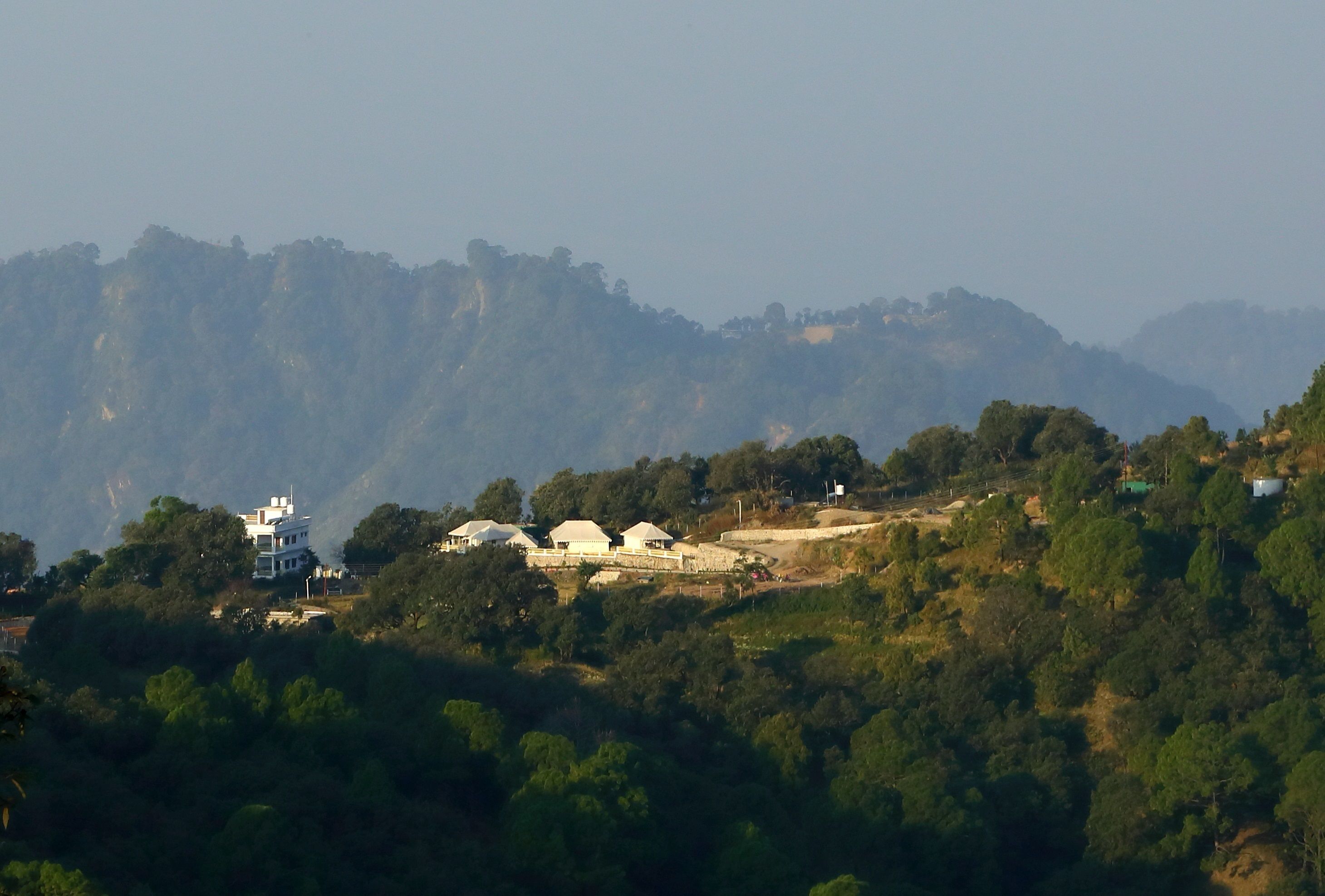 Un paysage montagneux avec un ensemble de bâtiments situés sur le versant d’une colline.