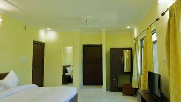 Habitación de hotel con cama, televisor, armario y escritorio.