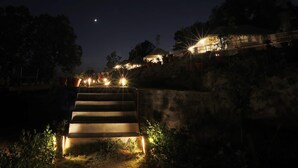 A nighttime view of a staircase leading up to a building with illuminated steps and surrounding trees. - Charekh Food & Forest Resort (Lansdowne)