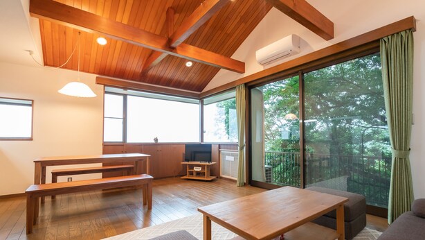 Un salón amplio con piso de madera, un ventanal grande y un balcón.