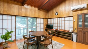 Una habitación tradicional japonesa con suelo de tatami, una mesa baja de tatami, armarios de madera y un televisor.