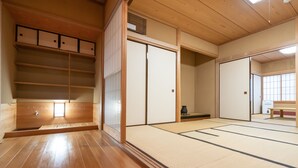 Una habitación japonesa tradicional con suelo de tatami, puertas correderas y estantes de madera.