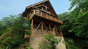 Eine hölzerne Turmkonstruktion mit Balkon, umgeben von dichtem Grün.