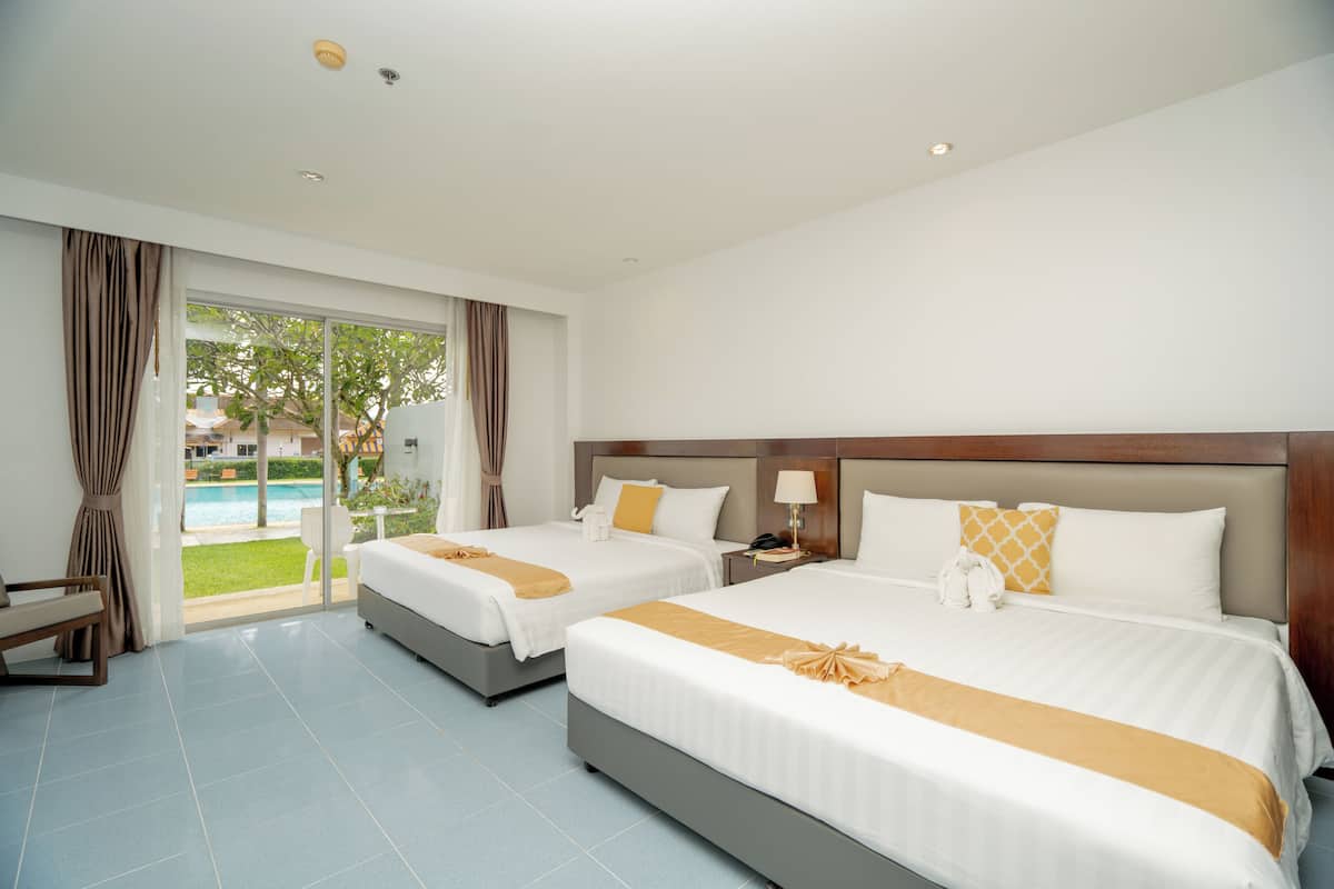 A hotel room with two beds, a view of a pool, and a balcony.