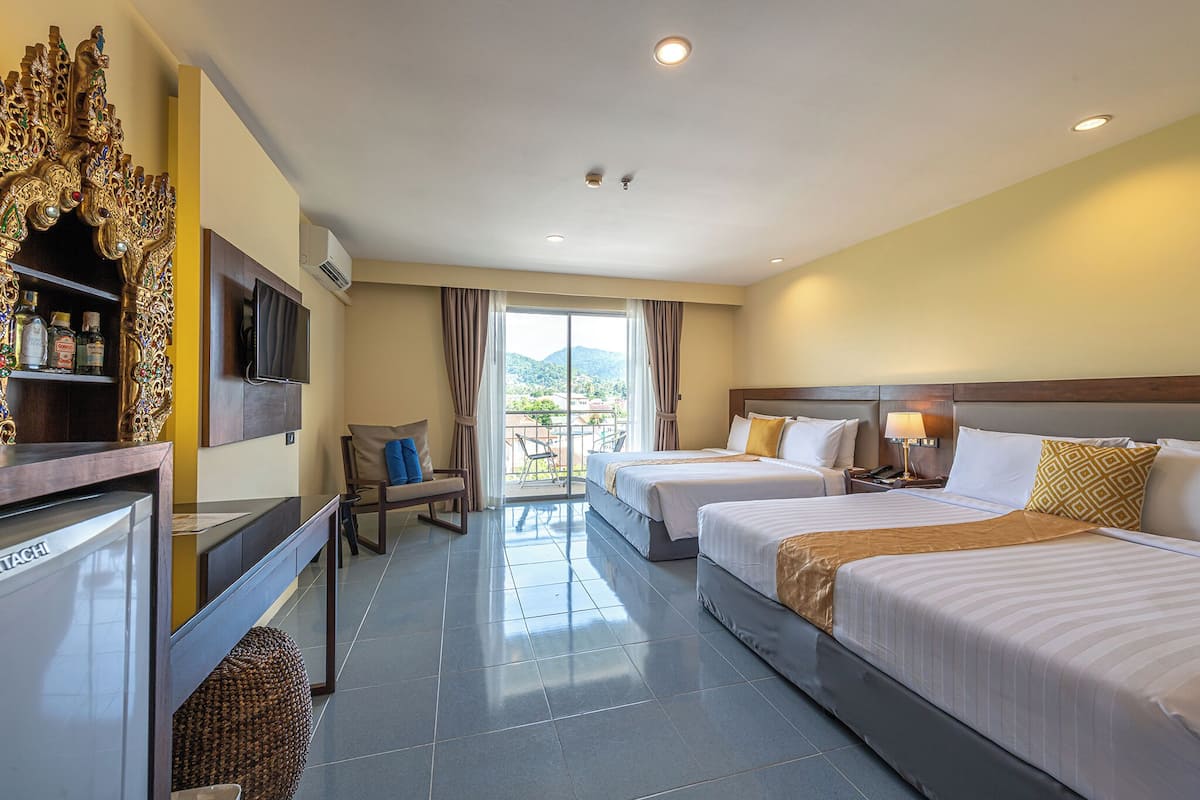 A hotel room with two beds, a TV, a minibar, and a balcony with a view of the mountains.