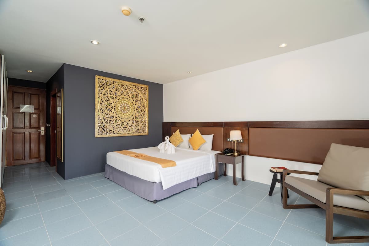 A hotel room with a bed, a chair, a nightstand, and a decorative wall piece.