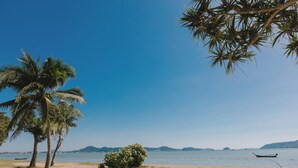 Una playa con palmeras, un bote y un cielo azul despejado.