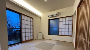 Una habitación con suelo de tatami, puertas correderas y un equipo de aire acondicionado.