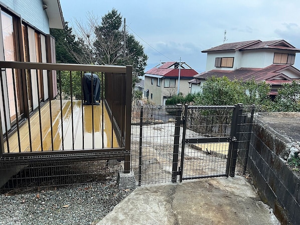 A gated area with a concrete path leading to a wooden deck.