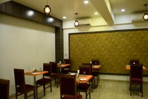 A restaurant with tables and chairs, recessed lighting, and an air conditioning unit on the wall.