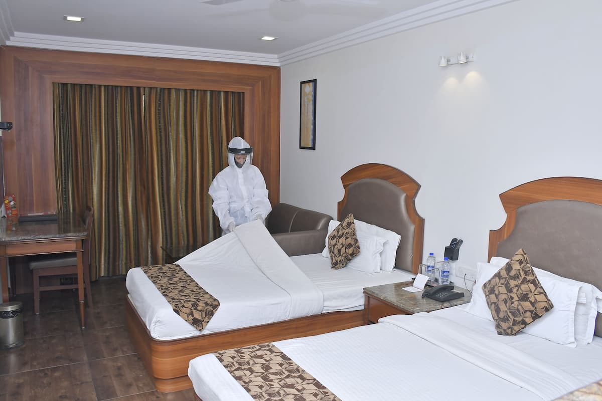 A hotel room with two beds, a desk, and a chair.