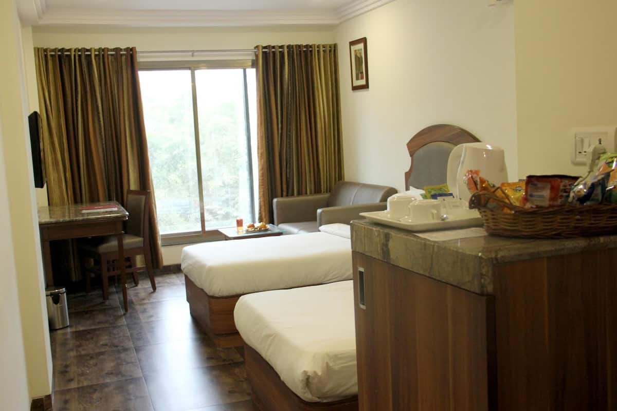 A hotel room with two beds, a desk, a chair, a mirror, and a breakfast tray.