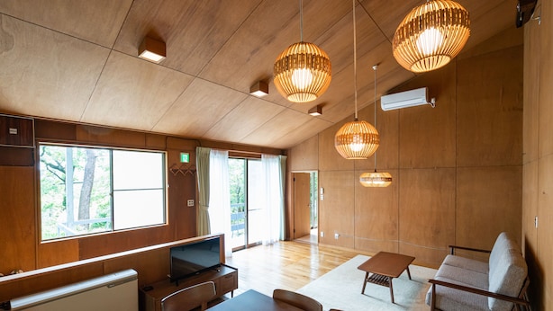 A spacious room with wooden walls and ceiling, large windows, a flat-screen TV, a dining table, and two sofas. - Angel Forest Izu Kogen (Ito)