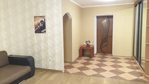 A living room with a patterned wallpaper, a wooden floor, a door with a unique design, and a small table with a sculpture. - Apartment Levanevskogo 7-53 (Odesa)