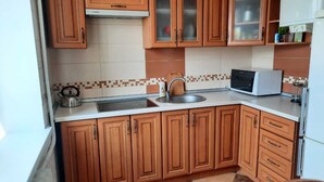 A kitchen with wooden cabinets, a microwave, a kettle, and a sink. - Apartment Levanevskogo 7-53 (Odesa)