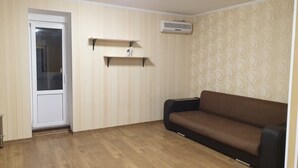 A room with a brown sofa, a door, and two shelves against the wall. - Apartment Levanevskogo 7-53 (Odesa)