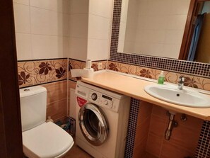 Een kleine badkamer met een wasmachine, toilet en wastafel.